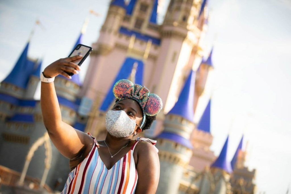 kuva nuoresta naisesta ottamassa selfietä Tuhkimon linnan edessä Magic Kingdomissa.