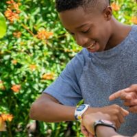 Photo of 2 boys using their MagicBand+ to interact with a Dory statue.