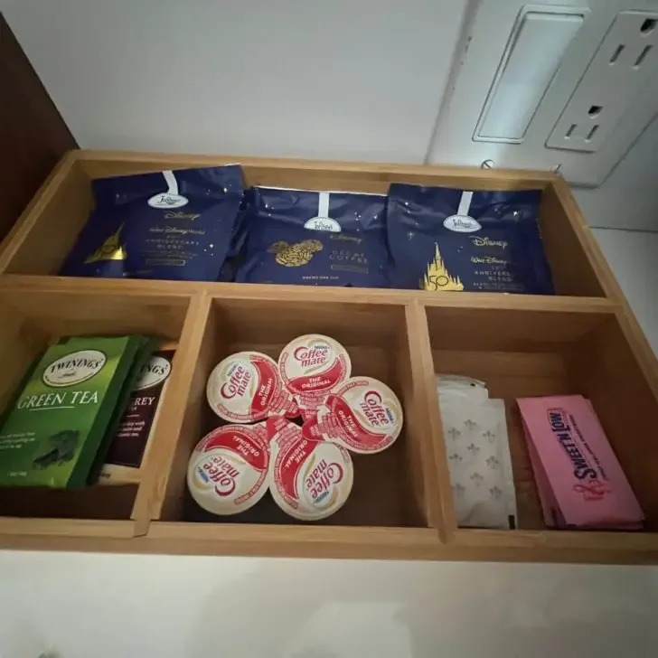 Closeup photo of a tea and coffee caddy with coffee pod packets, tea sachets, creamer pods, and sugar & sweet-n-low packets.