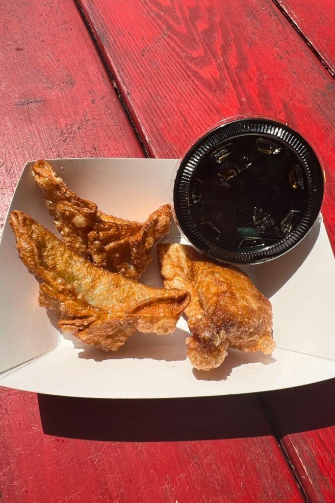 Photo of fried chicken dumplings in a paper basket with a cup of ponzu dipping sauce.