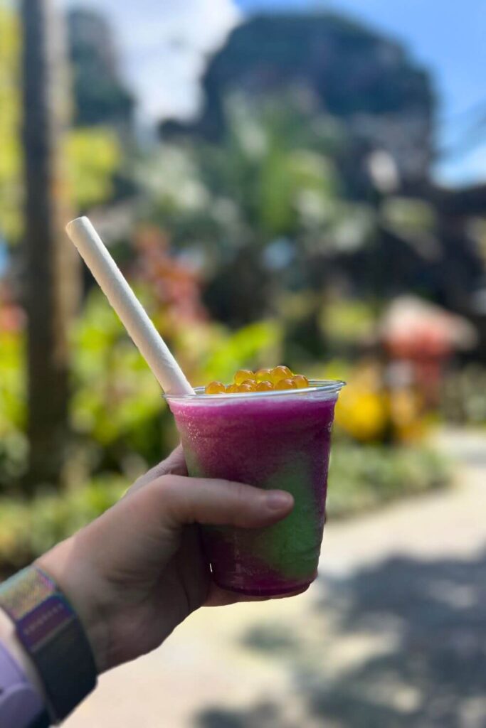 Photo of a pink and green night blossom slushy with sunny yellow passionfruit boba on top.