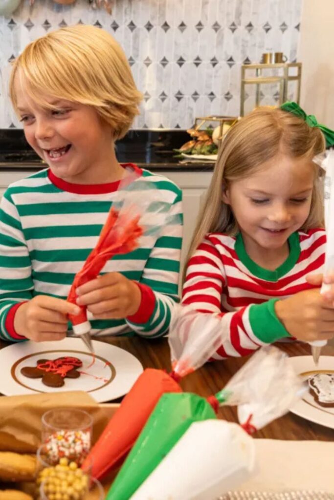 Two kids wearing Christmas pajamas decorate holiday cookies at the Waldorf Astoria Orlando.