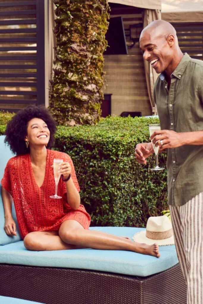 A man and woman relaxes at Waldorf Astoria Orlando's pool cabanas, while sipping champagne.