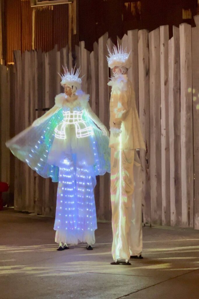 Photo of two stilt walking performers dressed as a icicles while posing with guests at Disney Springs.