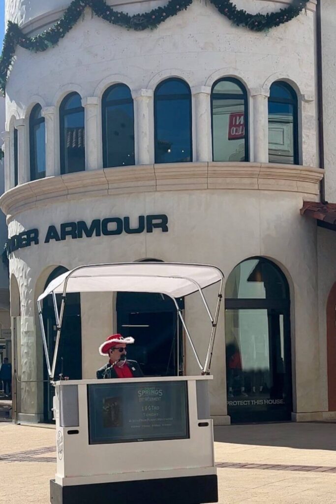 Photo of a man playing a piano that is motorized and driving around the open air Disney Springs area.