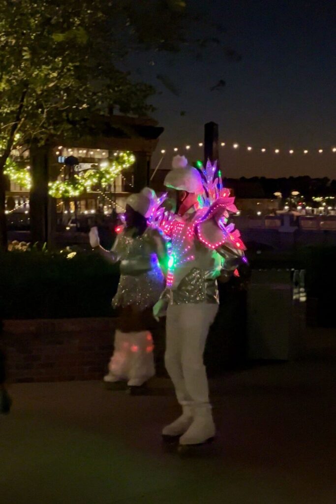 Photo of two roller skating performers at Disney Springs dressed as snowflakes with Christmas lights.